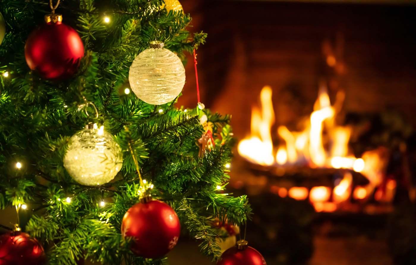 Christmas tree with bulbs and fireplace on in background