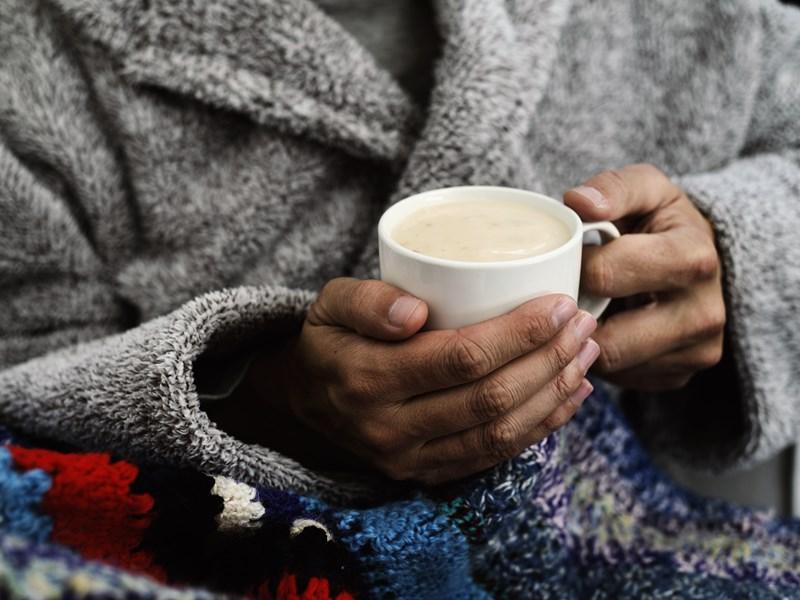 person holding cup of coffee in robe